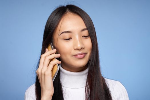 cute asian woman talking on the phone technology blue background. High quality photo