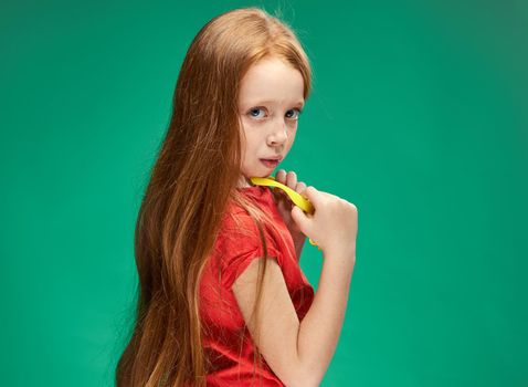 cheerful girl with red hair and a red t-shirt yellow glasses emotions studio. High quality photo