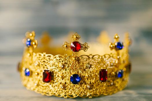 Golden crown encrusted with precious stones for wedding in the church, against a wooden background