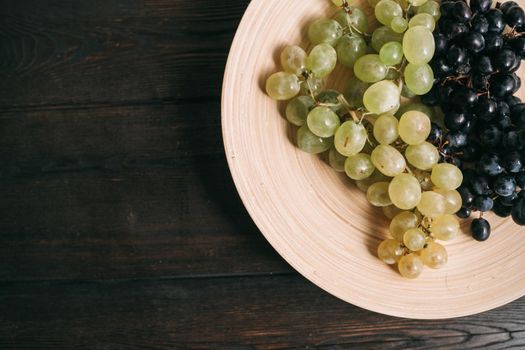 grapes in a plate on a wooden table top view fruits. High quality photo