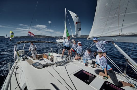 Croatia, Mediterranean Sea, 18 September 2019: The team of sailboat turns off the boat, sailboats compete in a sail regatta, The team works, pulls to a rope, the captain stands behind a steering wheel