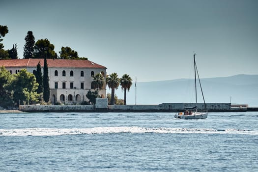 The race of sailboats, a regatta, reflection of sails on water, Intense competition, number of boat is on aft boats, island with windmills are on background