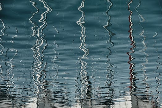 Reflection of masts of sailboats on water, interesting texture, smooth lines of water, a sail regatta, reflection of masts on water, ropes and aluminum