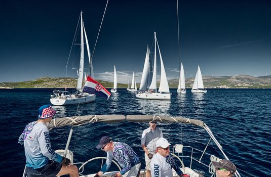 Sailboats compete in a sail regatta, the team turns off the boat, reflection of sails on water, multicolored spinnakers, number of boat is on aft boats, Croatia, Mediterranean Sea, 18 September 2019