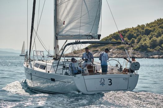 Croatia, Adriatic Sea, 15 September 2019: People have a good time on the sailboat, island with windmills are on background
