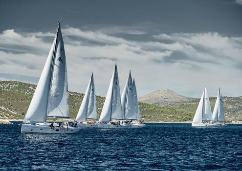 Croatia, Adriatic Sea, 18 September 2019: Sailboats compete in a sail regatta, sailboat race, reflection of sails on water, island is on background, clear weather