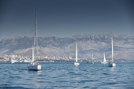 Croatia, Adriatic Sea, 15 September 2019: The race of sailboats, a regatta, reflection of sails on water, Intense competition, island with windmills are on background