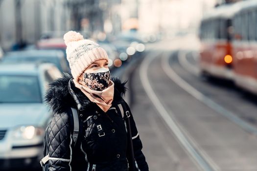 city streets with high traffic, cars and trams. woman with a mask on her face.