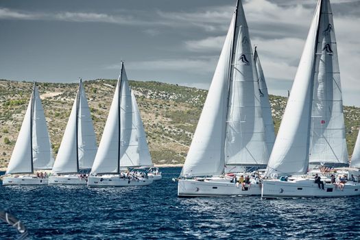 Croatia, Adriatic Sea, 18 September 2019: Sailboats compete in a sail regatta, sailboat race, reflection of sails on water, island is on background, clear weather