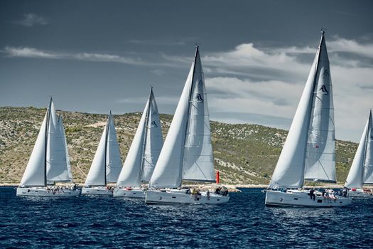 Croatia, Adriatic Sea, 18 September 2019: Sailboats compete in a sail regatta, sailboat race, reflection of sails on water, island is on background, clear weather