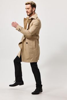 a man in trousers and a beige coat runs to the side on a light background. High quality photo