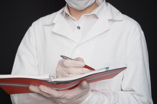 Science and medicine, a doctor in special clothes mask and rubber gloves with a notebook in his hands. High quality photo