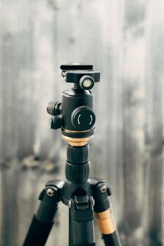 A small unbreakable black photo tripod on a gray wooden background