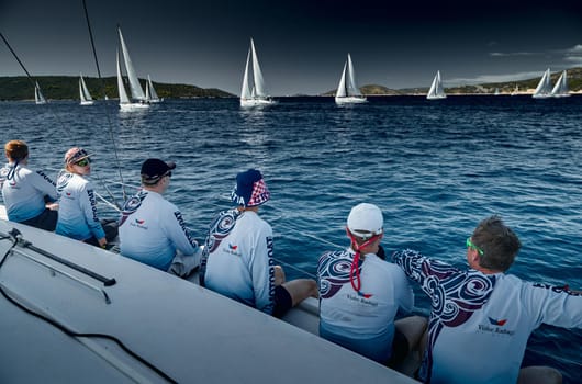 Croatia, Mediterranean Sea, 18 September 2019: The team of sailboat turns off the boat, sailboats compete in a sail regatta, The team works, pulls to a rope, the captain stands behind a steering wheel