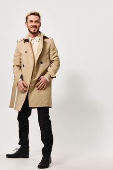 stylish guy in a beige coat holds his hands in his pocket and a blonde in a boot Copy Space. High quality photo