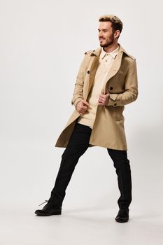 fashionable man in a beige coat trousers on a light background fashion trend of the season spring. High quality photo