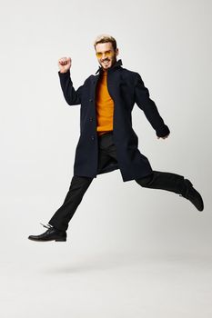 a man in stylish clothes, trousers and boots jumped up on a light background. High quality photo