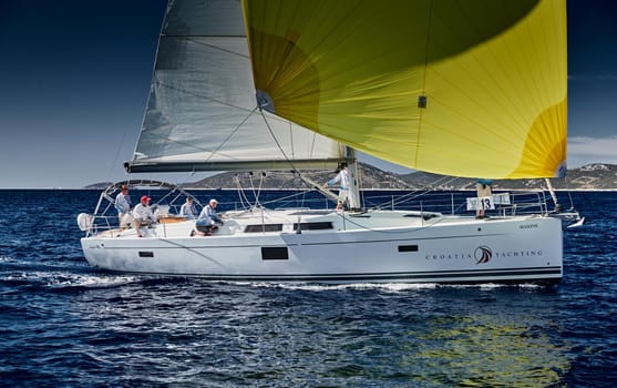 Croatia, Mediterranean Sea, 18 September 2019: The team of sailboat turns off the boat, sailboats compete in a sail regatta, The team works, pulls to a rope, the captain stands behind a steering wheel