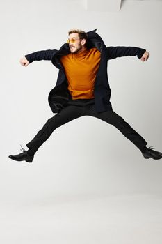 man jumped up with legs and arms spread wide orange sweater model. High quality photo
