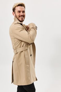 man fashion hairstyle beige coat studio light background. High quality photo