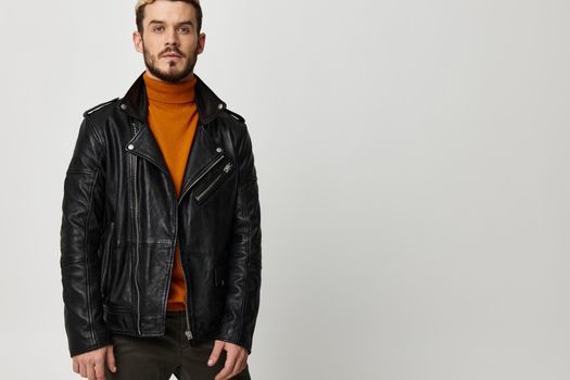 sexy young man in an orange sweater and in a leather jacket on a light background. High quality photo