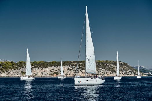 Croatia, Adriatic Sea, 15 September 2019: The race of sailboats, a regatta, reflection of sails on water, Intense competition, island with windmills are on background