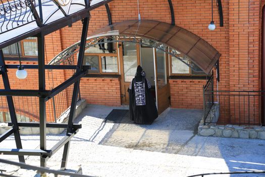 The entrance to the convent. A woman nun in black clothes at the door of the monastery.