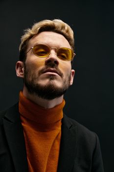 portrait of a fashionable man with glasses and an orange sweater jacket trend of the fall season new items. High quality photo