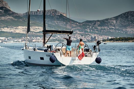 Croatia, Adriatic Sea, 15 September 2019: People have a good time on the sailboat, island with windmills are on background