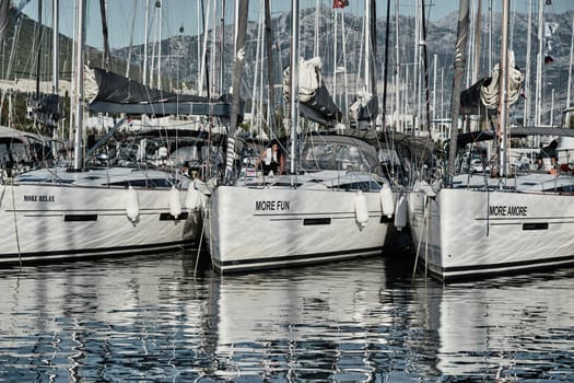 Croatia, Split, 15 September 2019: The number of sailboats with the blue sky and mountain on a background, a sail regatta, reflection of masts on water, ropes and aluminum