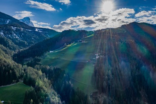 Aerial view of huge valley of the mountains of Italy, Trentino, Slopes with green spruce trees, Dolomites on background, The town in the bottom of a valley