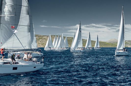 Croatia, Adriatic Sea, 18 September 2019: Sailboats compete in a sail regatta, sailboat race, reflection of sails on water, island is on background, clear weather