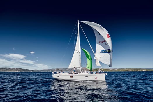 Croatia, Mediterranean Sea, 18 September 2019: The team of sailboat turns off the boat, sailboats compete in a sail regatta, The team works, pulls to a rope, the captain stands behind a steering wheel