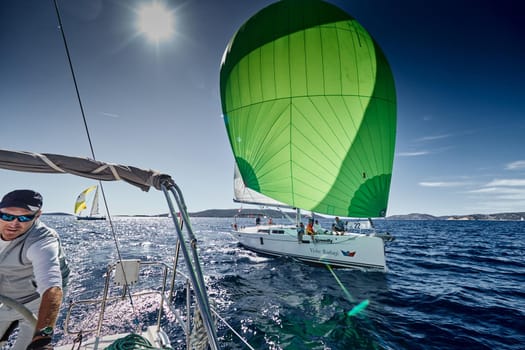 Croatia, Mediterranean Sea, 18 September 2019: The team of sailboat turns off the boat, sailboats compete in a sail regatta, The team works, pulls to a rope, the captain stands behind a steering wheel