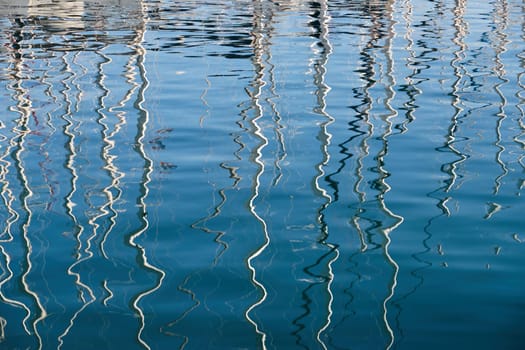 Reflection of masts of sailboats on water, interesting texture, smooth lines of water, a sail regatta, reflection of masts on water, ropes and aluminum