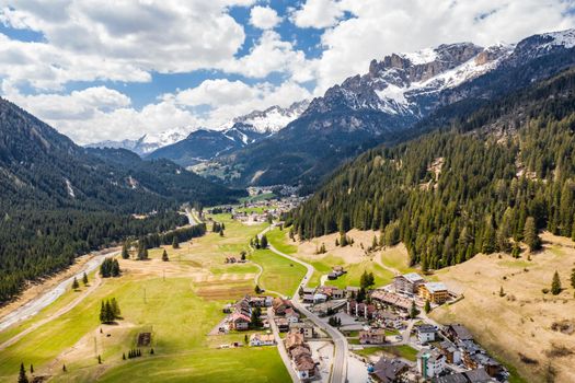 Aerial view of improbable green meadows of Italian Alps, Comano Terme, huge clouds over a valley, roof tops of houses, Dolomites on background, sunshines through clouds, sunny weather