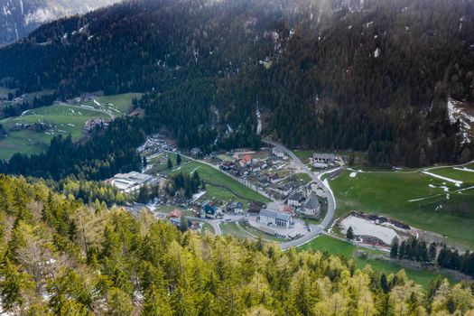 Aerial view of huge valley of the mountains of Italy, Trentino, Slopes with green spruce trees, Dolomites on background, The town in the bottom of a valley