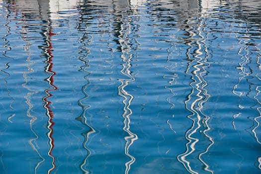 Reflection of masts of sailboats on water, interesting texture, smooth lines of water, a sail regatta, reflection of masts on water, ropes and aluminum