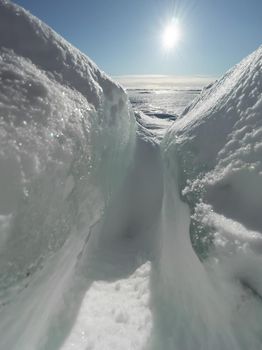 Ice slopes in sunny winter day, transparent ice of blue color, purely blue sky, long shadows, a pure snow-covered virgin soil, snow barkhans, . High quality photo