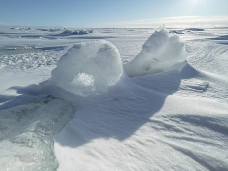 Ice slopes in sunny winter day, transparent ice of blue color, purely blue sky, long shadows, a pure snow-covered virgin soil, snow barkhans, . High quality photo