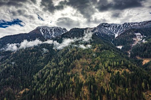 Aerial view of valley with green slopes of the mountains of Italy, Trentino, The trees tumbled down by a wind, huge clouds over a valley, green meadows, Dolomites on background