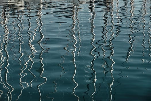 Reflection of masts of sailboats on water, interesting texture, smooth lines of water, a sail regatta, reflection of masts on water, ropes and aluminum