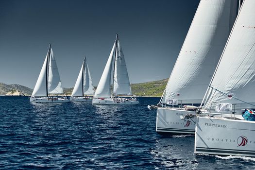 Croatia, Adriatic Sea, 18 September 2019: Sailboats compete in a sail regatta, sailboat race, reflection of sails on water, island is on background, clear weather