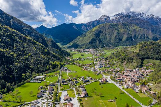 The Improbable aerial landscape of village Molveno, Italy, snow covered mountains Dolomites on background, roof top of chalet