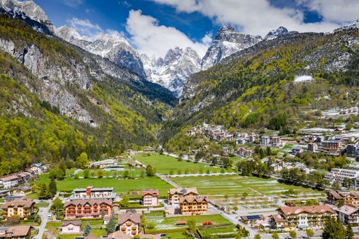 The Improbable aerial landscape of village Molveno, Italy, snow covered mountains Dolomites on background, roof top of chalet