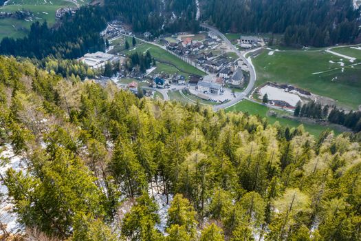 Aerial view of huge valley of the mountains of Italy, Trentino, Slopes with green spruce trees, Dolomites on background, The town in the bottom of a valley