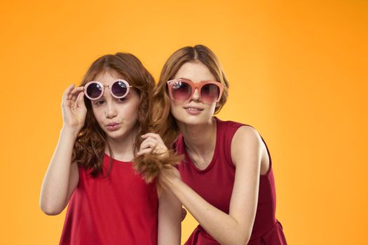 Two sisters and fun sunglasses fashion Friendship yellow background family. High quality photo
