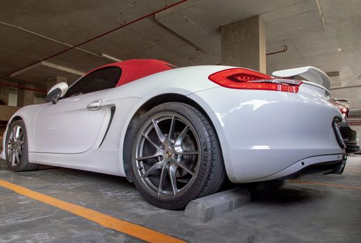 Bangkok, Thailand - 14 Jan 2021 : The side of Wheel of White Porsche Sports Car parked in the parking lot. Selective focus.