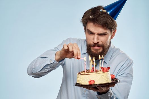 A man in a shirt with a cake in his hands and a festive cap on his head. High quality photo