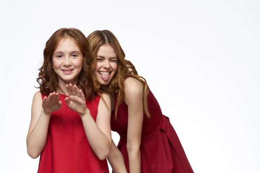 Cheerful mom and daughter next to red dresses hugs lifestyle light background smile. High quality photo